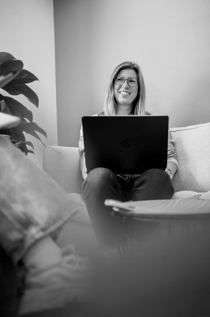 Schwarz-Weiß-Foto von Stefanie Seitz mit einem Laptop auf dem Sofa.